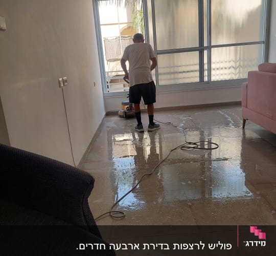 אדם מנקה רצפה עם מכונת פוליש ודלי אדום
